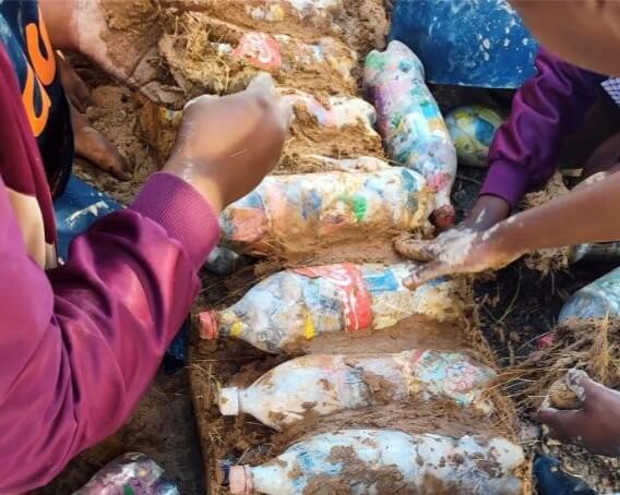 Young people using clay and bottles to build a structure