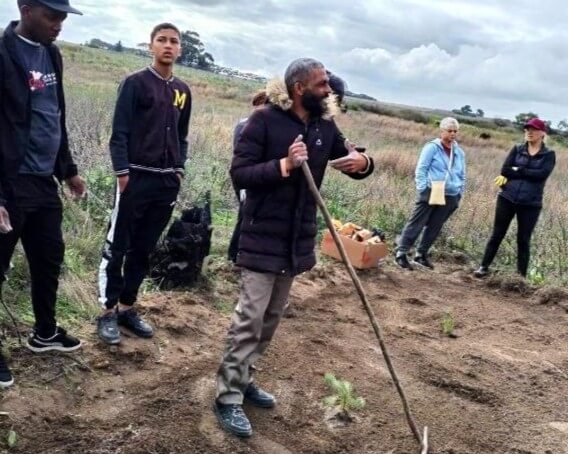 Group of people in garden, two holding rakes